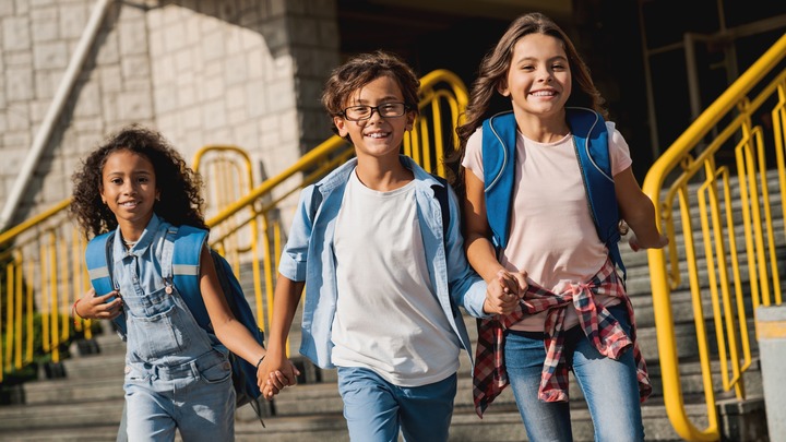 Drei Schulkinder laufen auf die Kamera zu