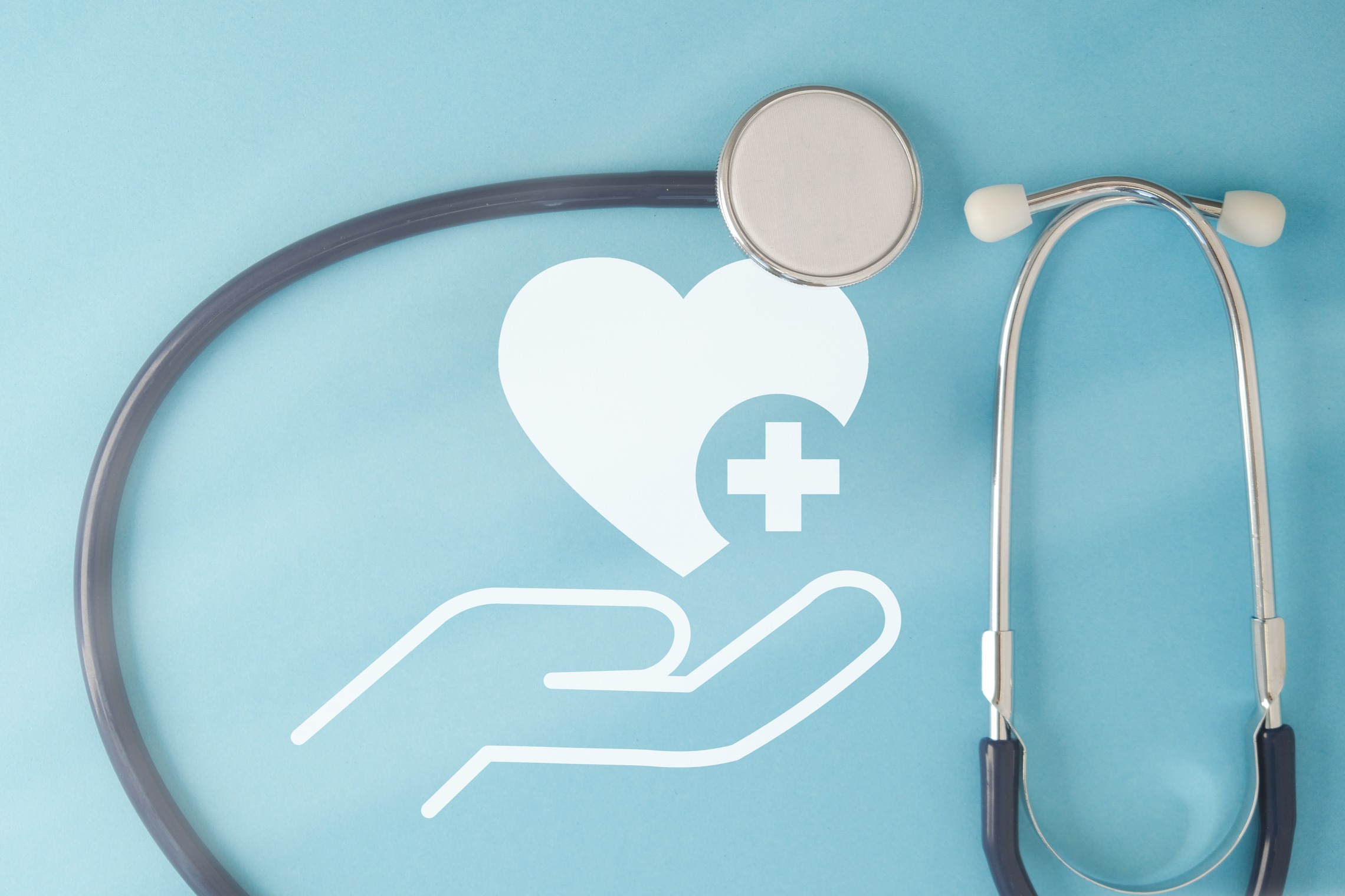 Betreuung & Absicherung Zeigt ein Bild mit einer Hand die Herz hält mit einem Stethoskop.